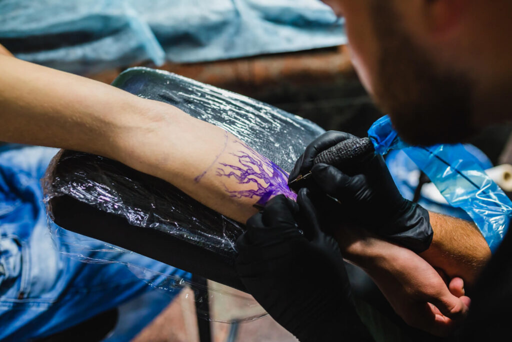 Artist making tattoo on arm