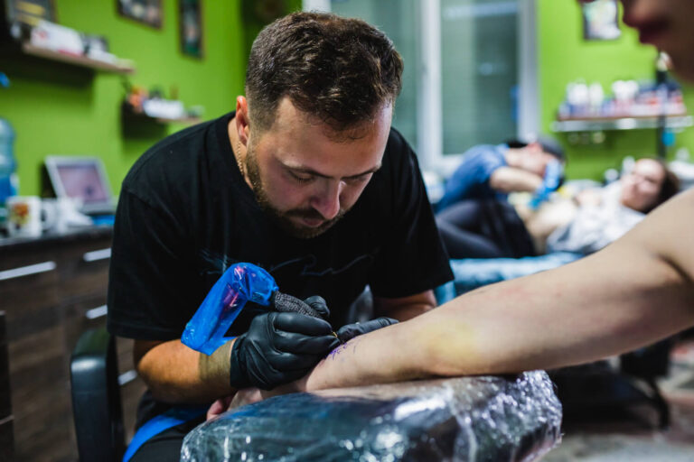 Man making tattoo on arm in salon